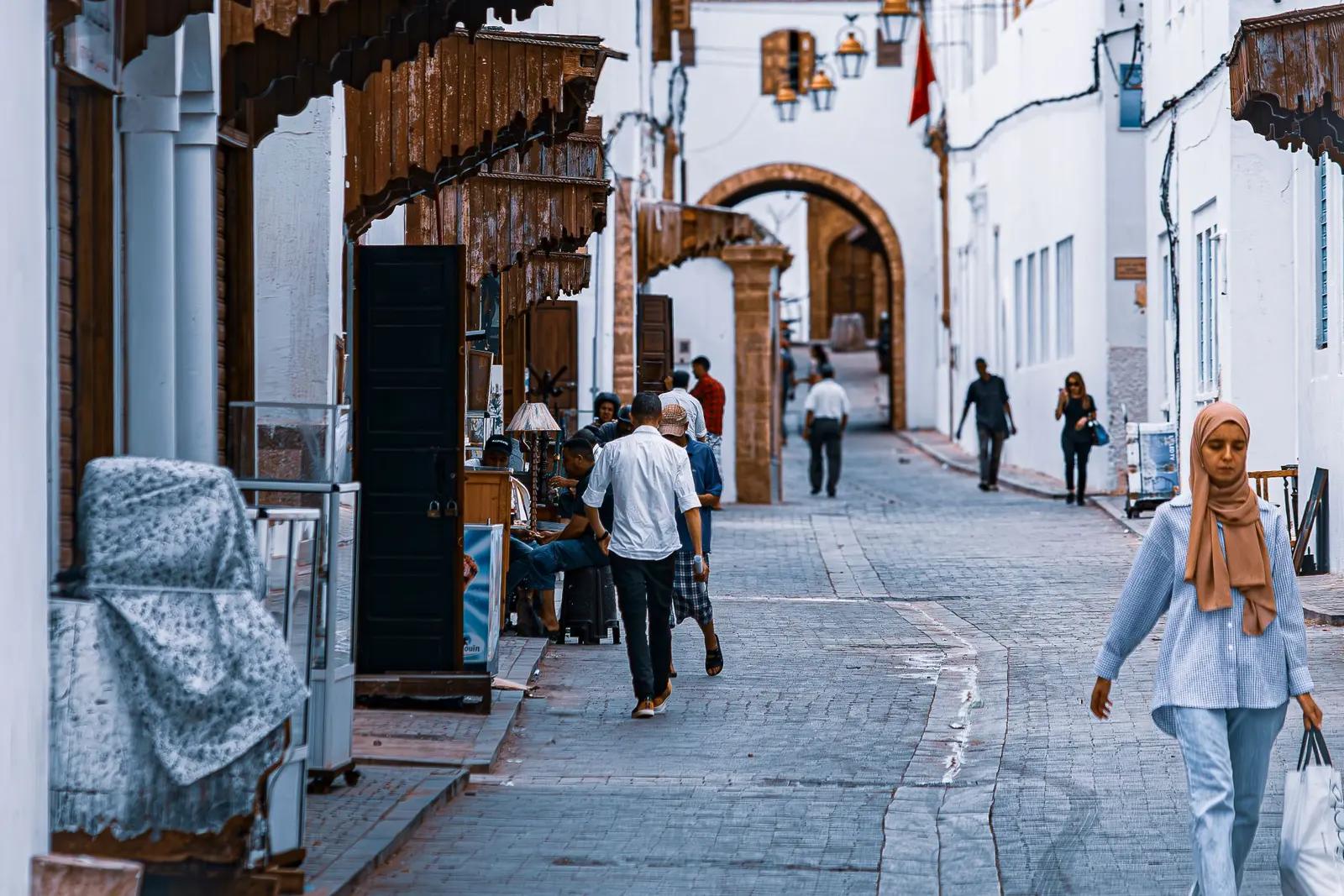A whitewashed street with hanging lanterns leading to an arched gate in Rabat