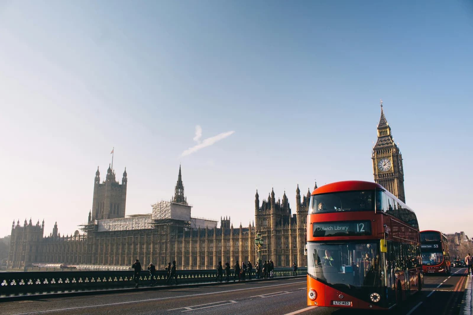 A red double-decker bus on Westminster Bridge passing Big Ben and the Houses of Parliament